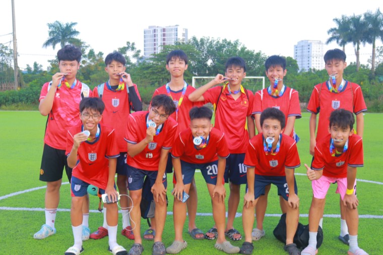 Một đội bóng chụp ảnh chung với huy chương trên sân cỏ nhân tạo